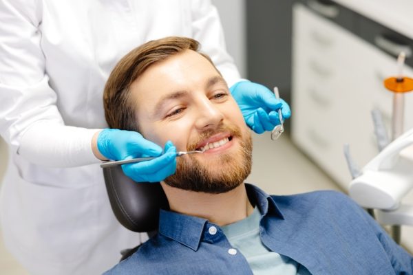 Portrait,Of,Happy,Man,Sitting,At,Dentist,Chair,In,Modern